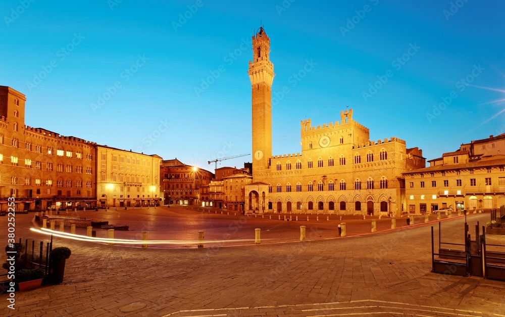 Early morning view of beautiful Campo Square (Piazza del Campo) in the center of Siena, a medieval town in Tuscany Italy, with Palazzo Pubblico & the famous Mangia Tower (Torre del Mangia) in twilight