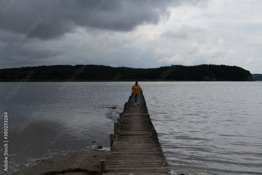 Fototapeta premium Holzsteg Wasser Gelbe Regejacke