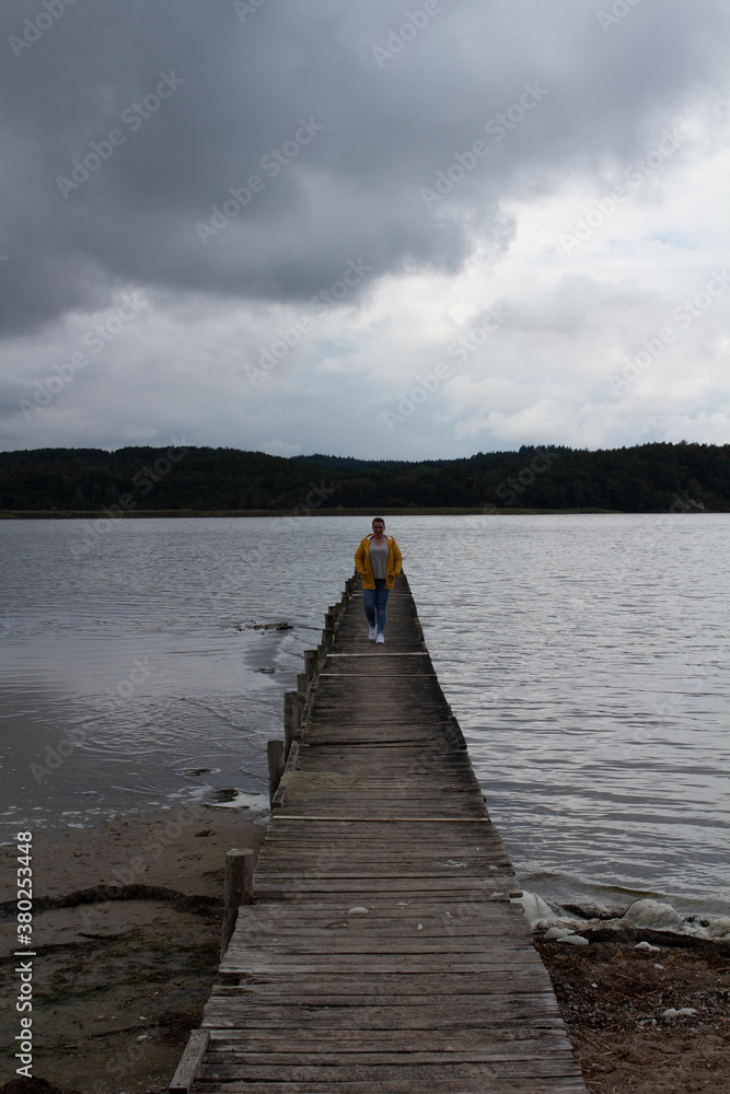 Fototapeta premium Holzsteg Wasser Gelbe Regejacke