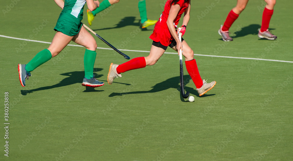 Three women battle for control of ball during field hockey game. Team sport concept.