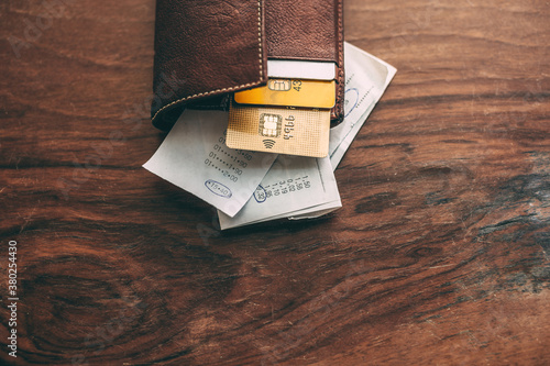 Credit card and some tickets inside a leather wallet on a wooden table. photo