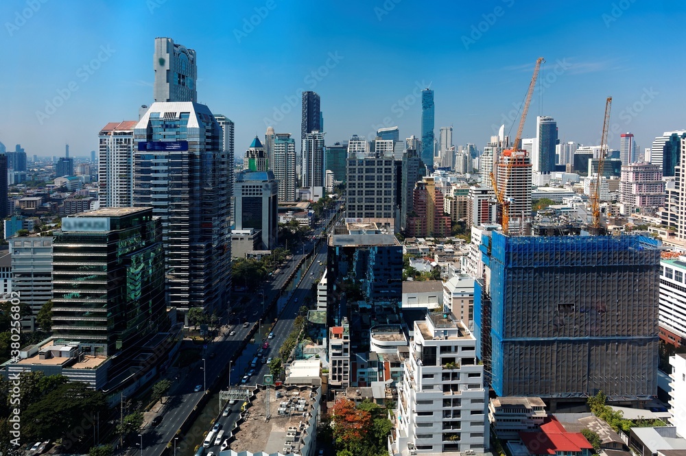 Obraz premium Cityscape of Bangkok, the fast developing capital city of Thailand, with busy traffic on the street and the famous landmark MahaNakhon Tower amid high rise buildings in background under blue sunny sky