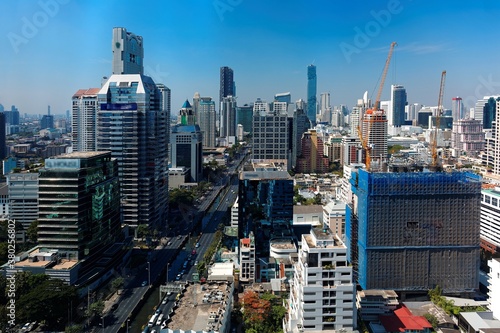 Cityscape of Bangkok, the fast developing capital city of Thailand, with busy traffic on the street and the famous landmark MahaNakhon Tower amid high rise buildings in background under blue sunny sky