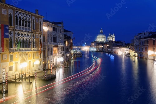 Night scenery of romantic Venice in blue twilight  with light trails of ferries  boats   ships cruising on the Grand Canal and majestic Basilica di Santa Maria della Salute illuminated in background