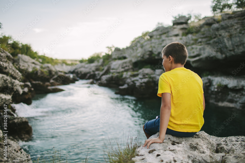Young boy sitting on cliff's edge Young boy sitting on cliff's edge