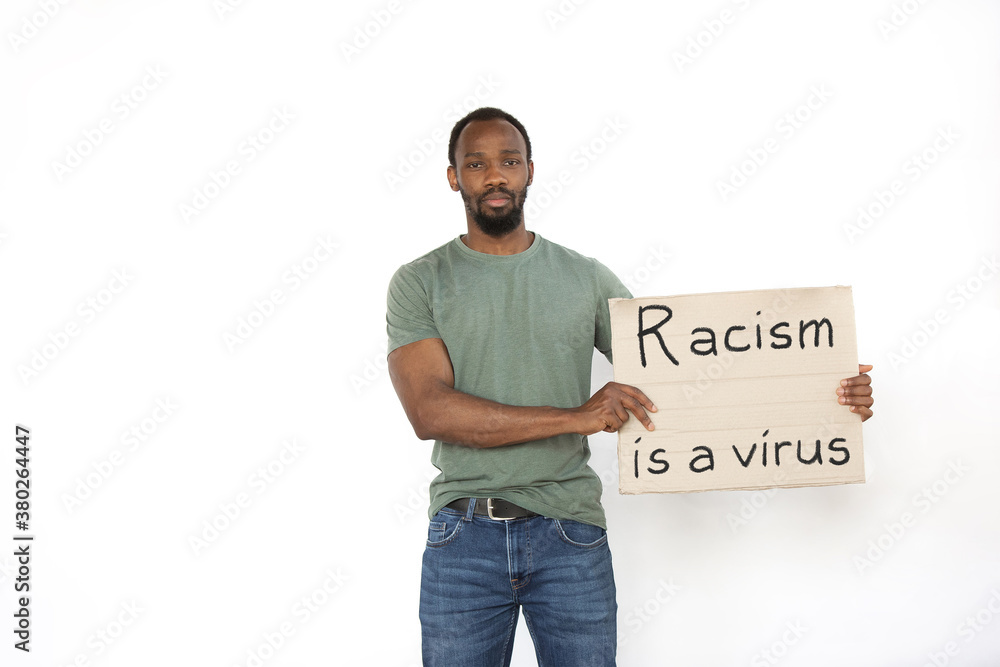 Racism is a virus. Young man protesting with sign isolated on white studio background. Activism, active social position, protest, actual problems. Meeting against human rights, abusing, racism. Racism is a virus. Young man protesting with sign isolated on white studio background. Activism, active social position, protest, actual problems. Meeting against human rights, abusing, racism.