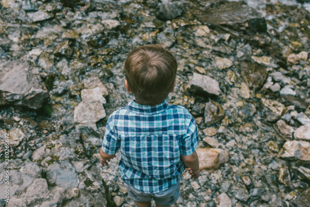 Nervous young boy about to cross a flowing stream of water Nervous young boy about to cross a flowing stream of water
