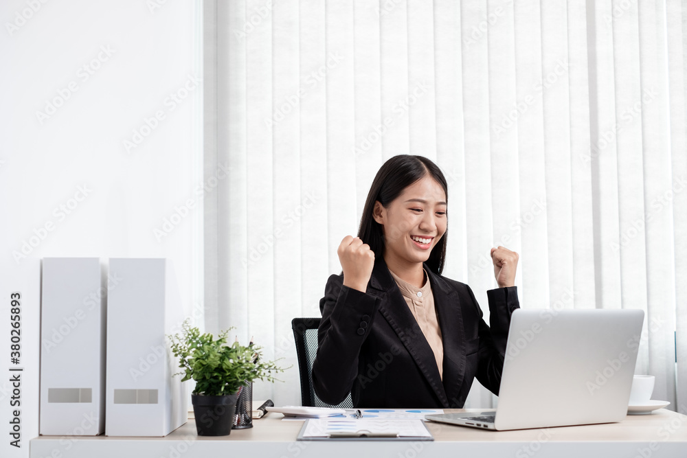 Asian businesswoman working on a laptop with a cheerful and happy smile while working at the office Asian businesswoman working on a laptop with a cheerful and happy smile while working at the office