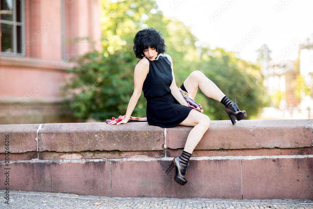 Fototapeta premium Junge Frau postet im schwarzen Kleid im Freien