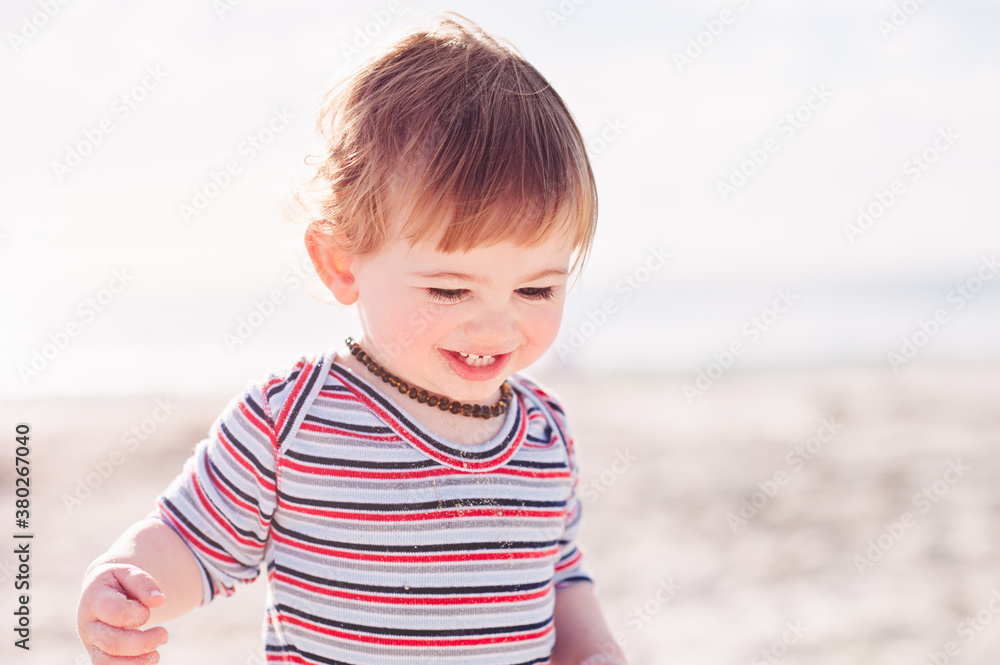 Happy toddler having fun at the beach on a winter afternoon Happy toddler having fun at the beach on a winter afternoon