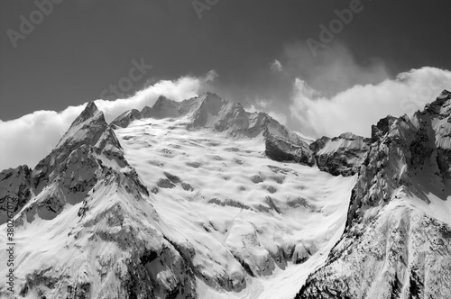 Black and white view from ski slope on snowy glacier and mountain peaks