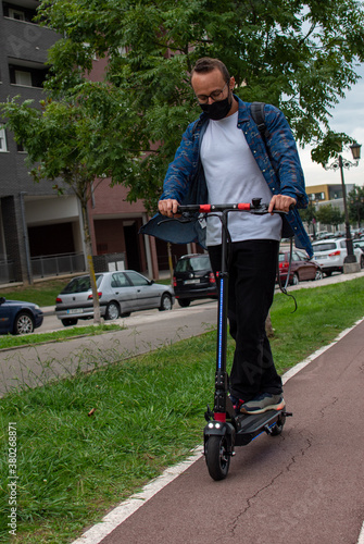 man with mask rides his electric scooter with the lights on