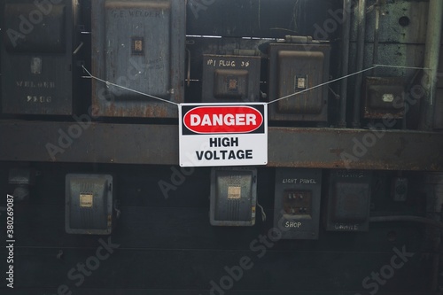 A Danger High Voltage hangs on some old dirty electrical boxes.