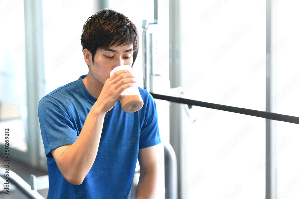 ジムでプロテインを飲む男性