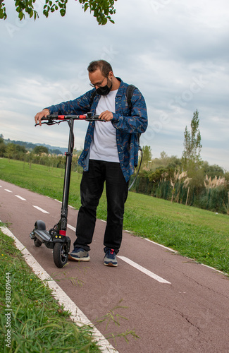 man with a mask looks at his electric scooter