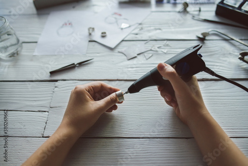 Jeweler working on the silver ring with electric engraver