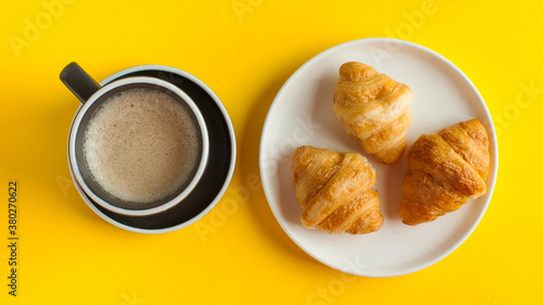 Banner coffee mug cappuccino and croissant on a yellow background. Minimalism. Sweet food, delicious Breakfast.