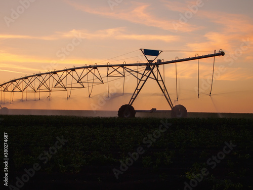 Fototapet Center pivot irrigation system in the farm field at sunset