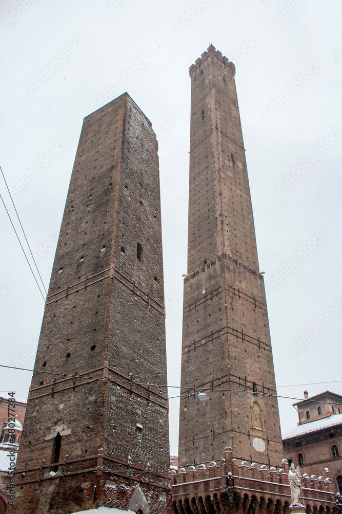 Close up. Asinelli tower of Bologna in the winter, coverd by snow. White sky in background. Emilia Romagna region ( Italy )