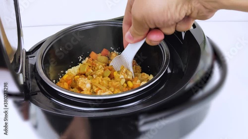 Macro Video of a multicooker. The man opens the pan and mixes the dish. Steam can be seen from the cooked food. The concept of cooking automation and ease in the kitchen. photo