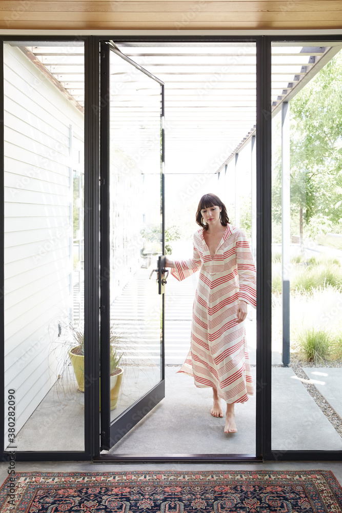 Woman walking into entrance of modern design home Woman walking into entrance of modern design home