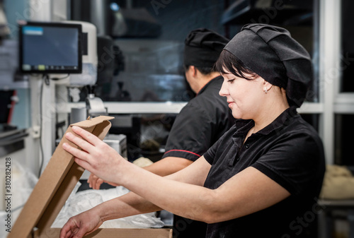 bakers in black uniform at the pizzeria kitchen working on order