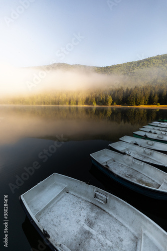 Boats on the lake in the wilderness forest. Magical misty landscape. Lake Sfanta Ana Romania Transylvania.