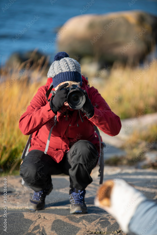 Woman photographer taking pictures with SLR camera at seashore in autumn Woman photographer taking pictures with SLR camera at seashore in autumn