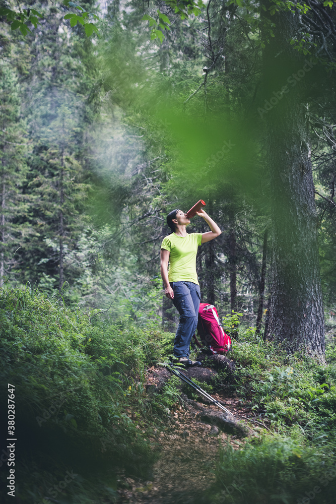 Female hiker drinks water inside the forest Female hiker drinks water inside the forest