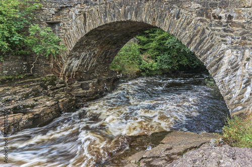 The old Bridge of Dochart, where the River Dochart flows through the village of Killin in the highlands of Scotland, near the area of waterfalls and white water rapids known as the Falls of Dochart.