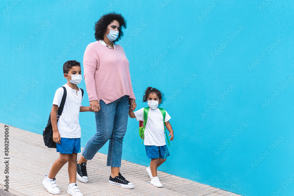 Obraz premium Mother with son and daughter going back to school wearing face masks - Coronavirus lifestyle and family concept - Main focus on mum