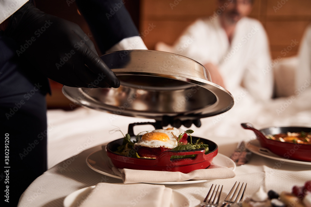 Photography Waiter in rubber gloves opening the frying pan with lunch in it
