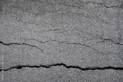 cracked asphalt concrete background. damaged road surface caused by torrential rainfall or earthquake disaster.