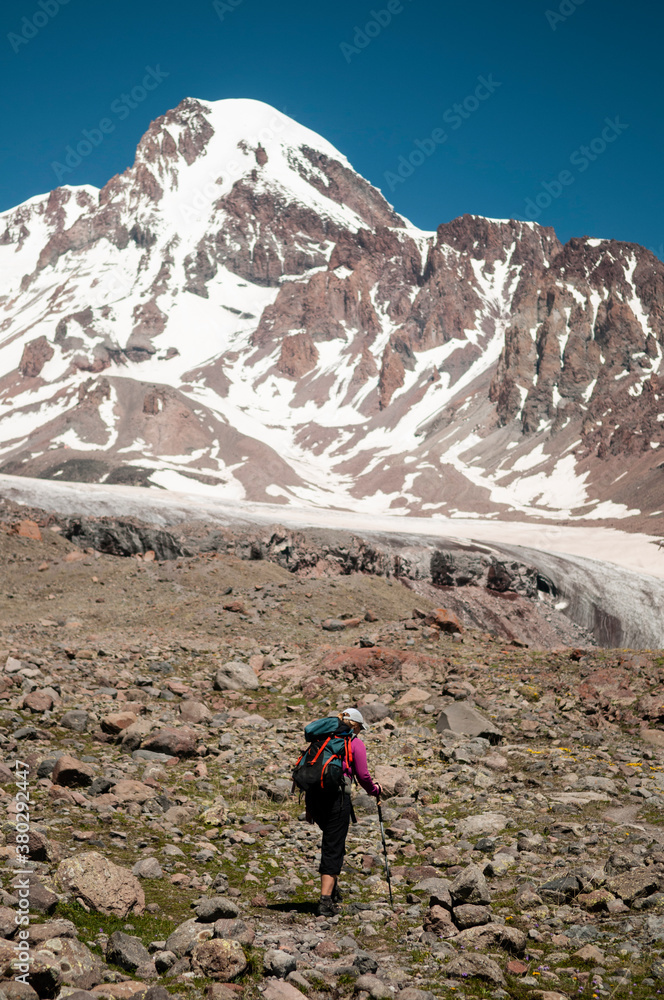 Woman trekker walking towards Mount Kazbek, Caucasus Mountains, Georgia. Woman trekker walking towards Mount Kazbek, Caucasus Mountains, Georgia.