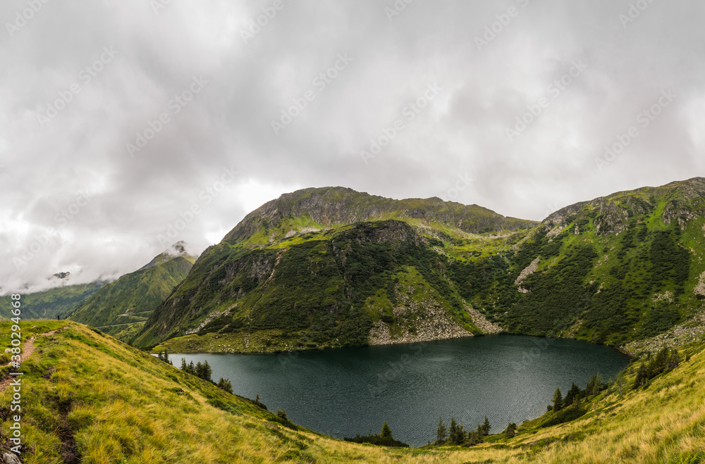mountain lake with green grasses and trees panorama