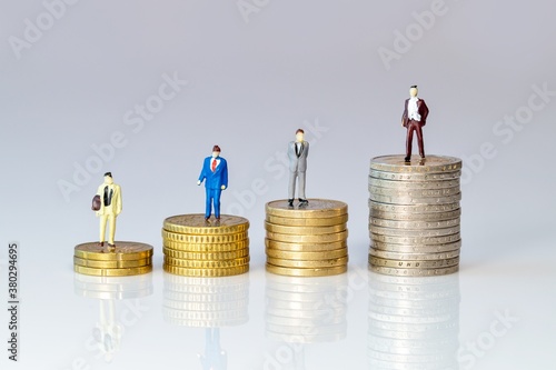 Business toy people standing on stack of Euro coins. figurine symbol for increasing or reduction expenses for salarys. miniature businessman on increasing high stack of coins, money