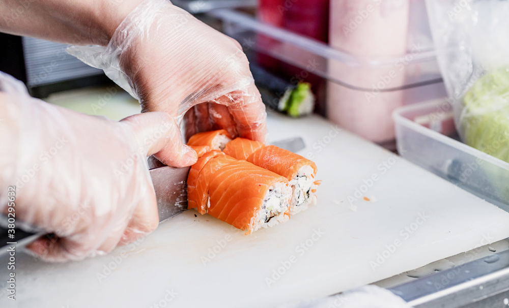 Sushi chef slicing rolls
