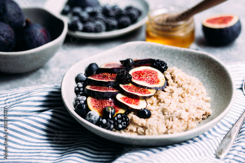 Oatmeal with figs, wild berries and honey in a plate. 