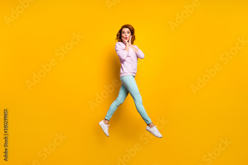 Full length photo of astonished funny girl rest relax look unbelievable black friday bargain impressed jump touch hands face wear casual style outfit isolated over shine color background