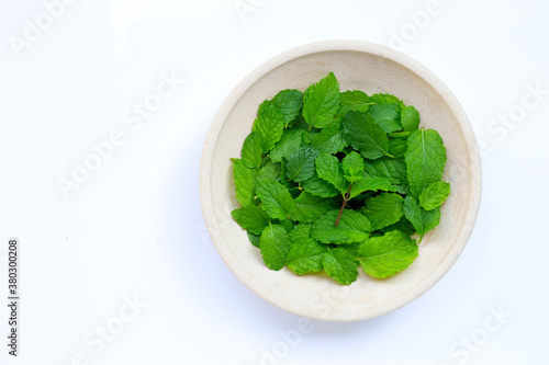 Fresh mint leaves in pottery plate on white background.
