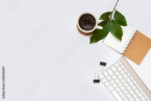 Office table top. Workspace with blank board with clip, keyboard, stationery, pencil, coffee cups on light gray background. Place for text