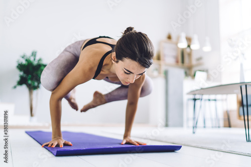 Focused woman doing yoga handstand at home