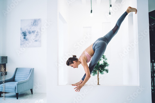 Flexible woman doing yoga in spacious room