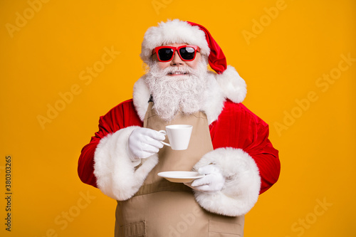 Close-up portrait of his he nice attractive cheerful cheery confident Santa shop owner drinking latte beverage cappuccino isolated bright vivid shine vibrant yellow color background