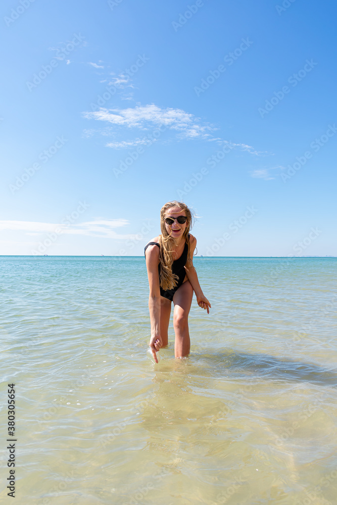Fototapeta premium Woman in black swimsuit on the beach