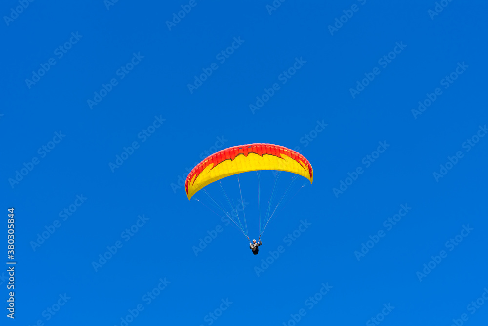 Paraglider in the blue sky. The sportsman flying on a paraglider. Paraglider in the blue sky. The sportsman flying on a paraglider.