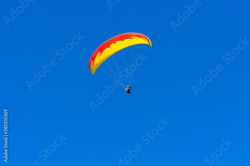 Paraglider in the blue sky. The sportsman flying on a paraglider.