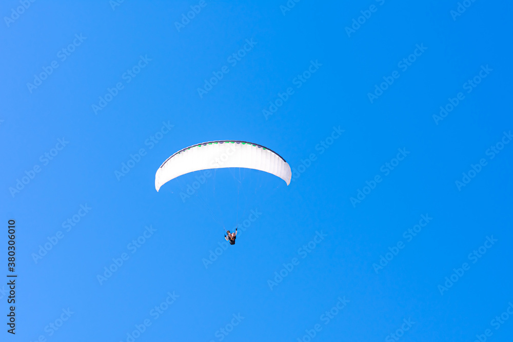 Paraglider in the blue sky. The sportsman flying on a paraglider. Paraglider in the blue sky. The sportsman flying on a paraglider.