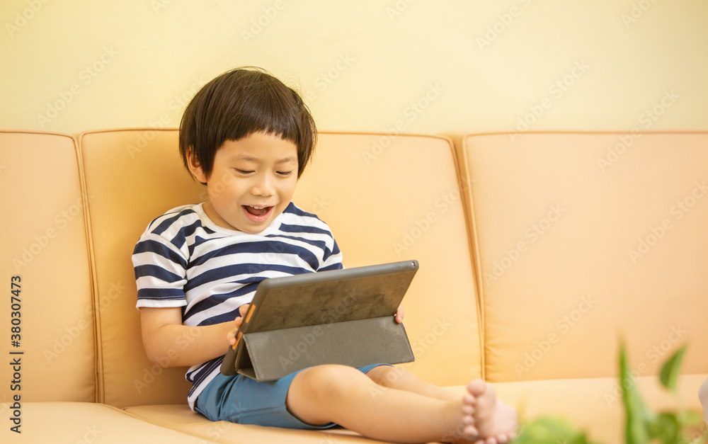 Happy boy sitting on couch with Tablet computer Happy boy sitting on couch with Tablet computer