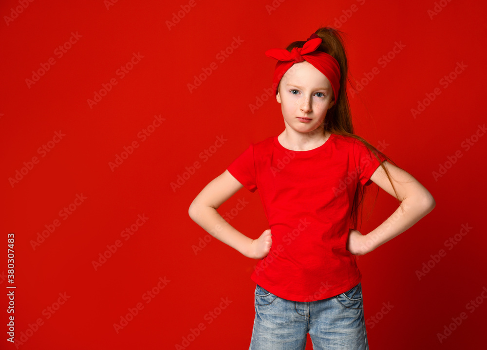 Cute little red-haired girl sulking and frowning while holding hands on the waist, offended and disappointed Cute little red-haired girl sulking and frowning while holding hands on the waist, offended and disappointed
